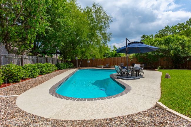 View of swimming pool with a fenced backyard, a fenced in pool, a yard, and a patio | Image 32