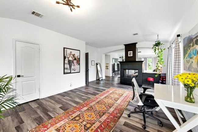 Living area featuring arched walkways, wood finished floors, vaulted ceiling, and a tile fireplace | Image 20