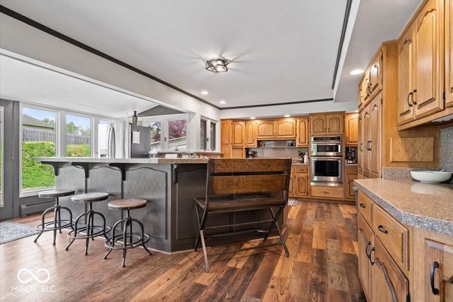 kitchen featuring stainless steel appliances, a kitchen bar, dark wood-style flooring, tasteful backsplash, and recessed lighting | Image 15