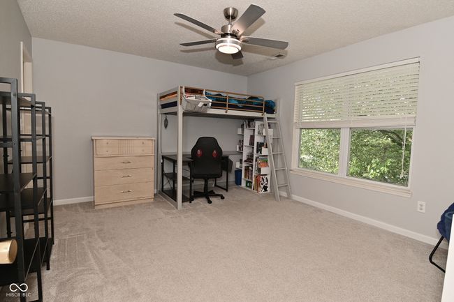 bedroom with carpet flooring, a textured ceiling, baseboards, and a desk | Image 35
