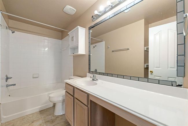Spacious secondary bathroom offers a dual-sink vanity, large framed mirror, tile flooring, and a tiled shower/tub combo great for shared use or busy mornings. | Image 13