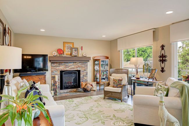 Warm inviting living room with wood-burning fireplace. Upgrades include smooth ceilings, recessed lighting, dual-pane windows, custom window coverings and gorgeous luxury vinyl flooring in the common rooms. | Image 7
