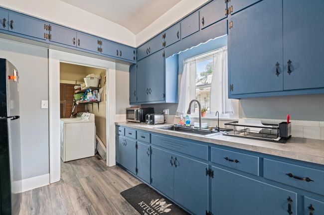 Kitchen with blue cabinetry, a sink, freestanding refrigerator, and washing machine and dryer | Image 30