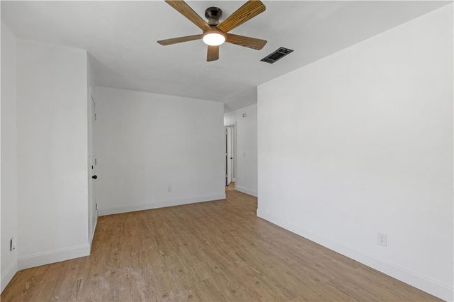 Empty room featuring light wood-style flooring, a ceiling fan, visible vents, and baseboards | Image 6