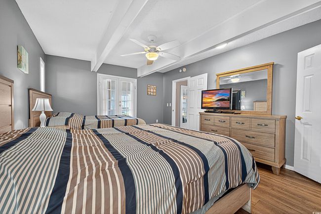 Bedroom with wood finished floors, french doors, beamed ceiling, and a ceiling fan | Image 14