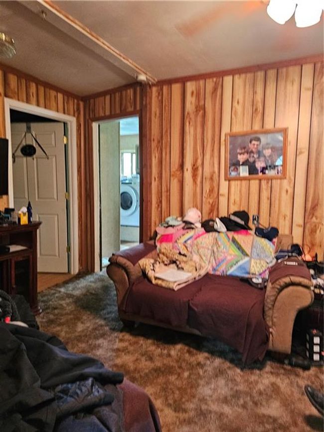 Bedroom with wood walls, washer / clothes dryer, and carpet floors | Image 4