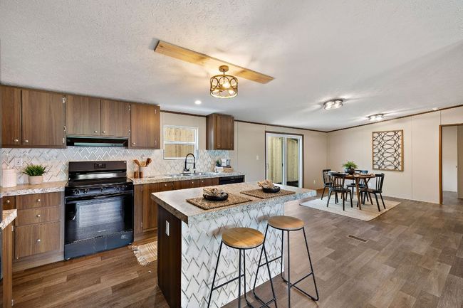 Kitchen with a sink, electric range, dark wood finished floors, backsplash, and under cabinet range hood | Image 19