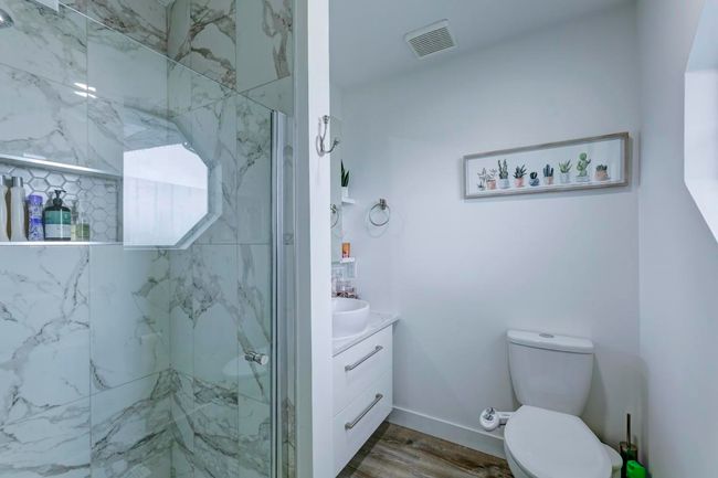 Bathroom with a marble finish shower, toilet, visible vents, wood finished floors, and vanity | Image 27