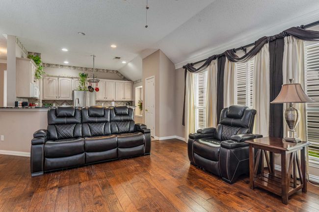 Living area with lofted ceiling, hardwood finished floors, baseboards, recessed lighting. | Image 17