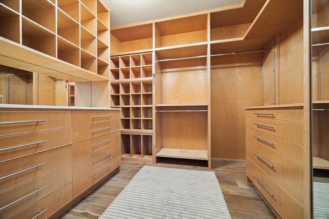One of two expansive primary closets, featuring custom built-ins, abundant drawer storage, open shelving for accessories, and dedicated shoe cubbies. Thoughtfully designed for optimal organization and luxury living. | Image 19