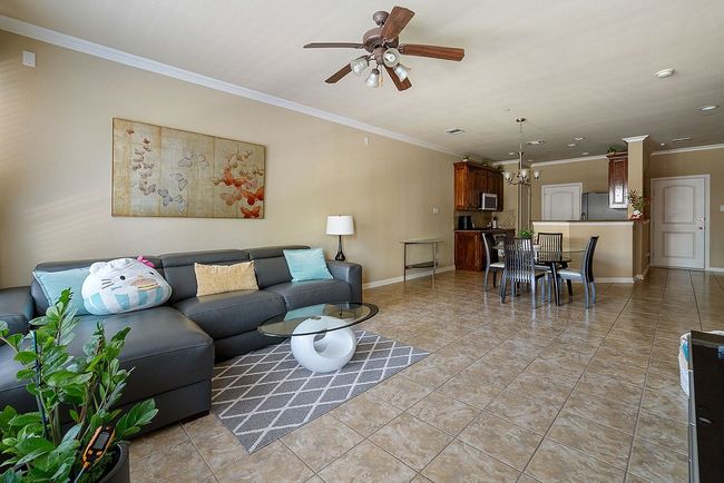 Living area with light tile patterned floors, crown molding, ceiling fan, baseboards, and recessed lighting | Image 23