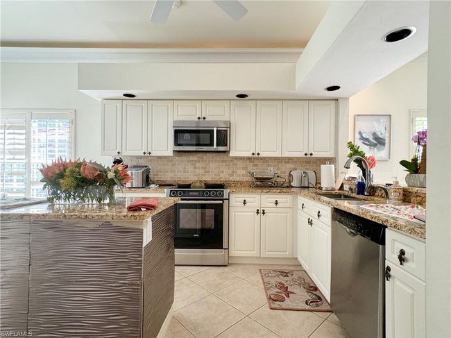 Kitchen with ceiling fan, light tile floors, sink, white cabinetry, and appliances with stainless steel finishes | Image 42