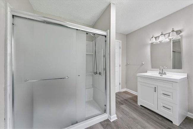 Bathroom featuring a shower stall, wood finished floors, vanity, and a textured ceiling | Image 56