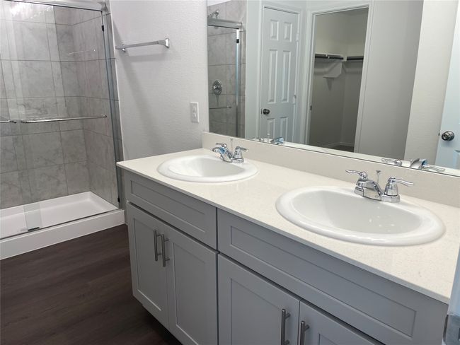 Full bathroom with a stall shower, a walk in closet, double vanity, and wood finished floors | Image 15