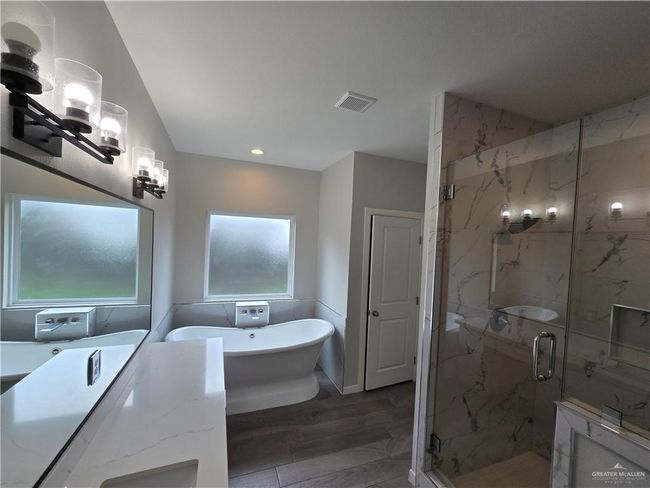 Bathroom featuring a marble finish shower, a soaking tub, wood finished floors, recessed lighting, and vanity | Image 10