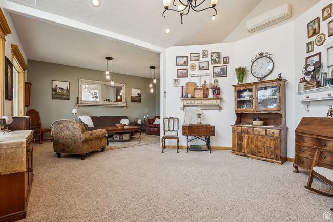 Living area featuring a chandelier, carpet floors, an AC wall unit, and baseboards | Image 8