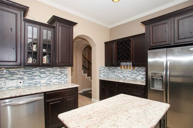 Kitchen featuring appliances with stainless steel finishes, dark brown cabinets, tasteful backsplash, arched walkways, and crown molding | Image 13