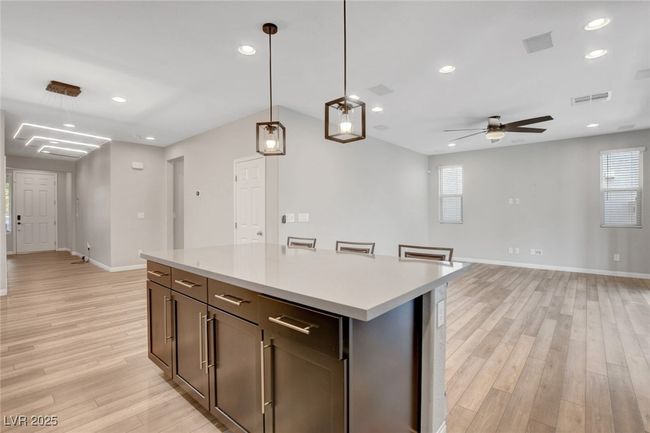Kitchen with light wood-style floors, baseboards, ceiling fan, light countertops, and decorative light fixtures | Image 19