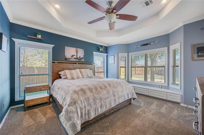 Carpeted bedroom with a raised ceiling, multiple windows, ornamental molding, a ceiling fan, and recessed lighting | Image 16