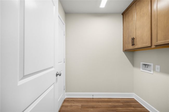 Washroom with cabinet space, hookup for a washing machine, baseboards, and dark wood-style floors | Image 12