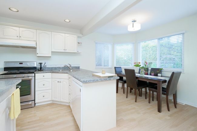 Kitchen featuring under cabinet range hood, stainless steel range with gas cooktop, a sink, a peninsula, and light wood-style flooring | Image 9