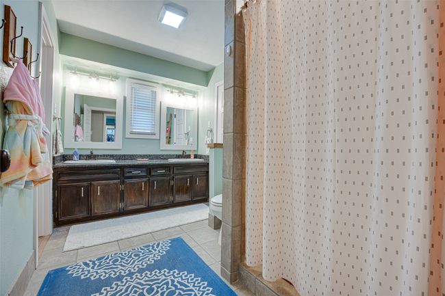 Bathroom with double vanity, tile patterned flooring, and a shower with curtain | Image 25