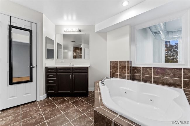 Bathroom with tile patterned floors, baseboards, vanity, and a tub with jets | Image 35