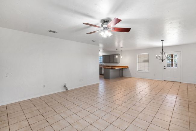 Unfurnished living room with a chandelier, ceiling fan, and light tile patterned floors | Image 10