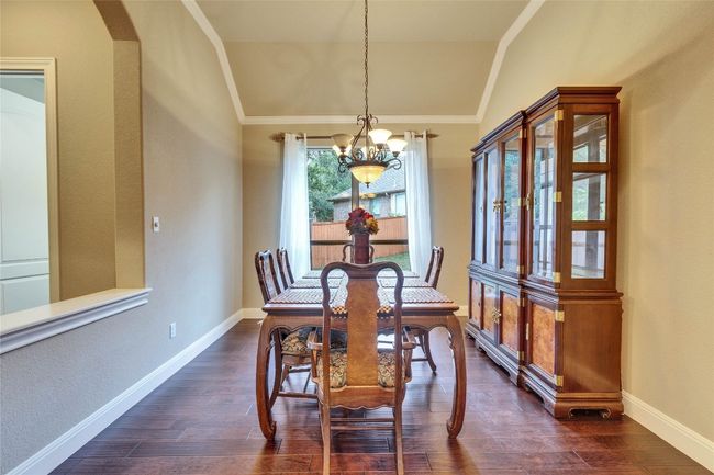 Dining room featuring a chandelier, lofted ceiling, crown molding, dark wood finished floors, and arched walkways | Image 10