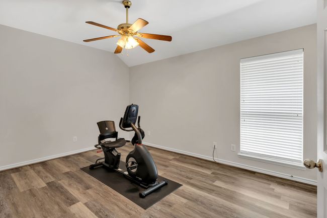 Workout or Exercise room featuring ceiling fan, vaulted ceiling, wood finished floors, and baseboards | Image 26