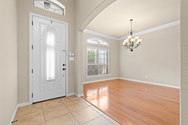 Entrance foyer with a chandelier, light tile patterned flooring, crown molding, and arched walkways | Image 8