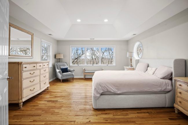 The spacious primary suite features a stunning tray ceiling and large windows that fill the room with natural light and serene treetop views. | Image 21