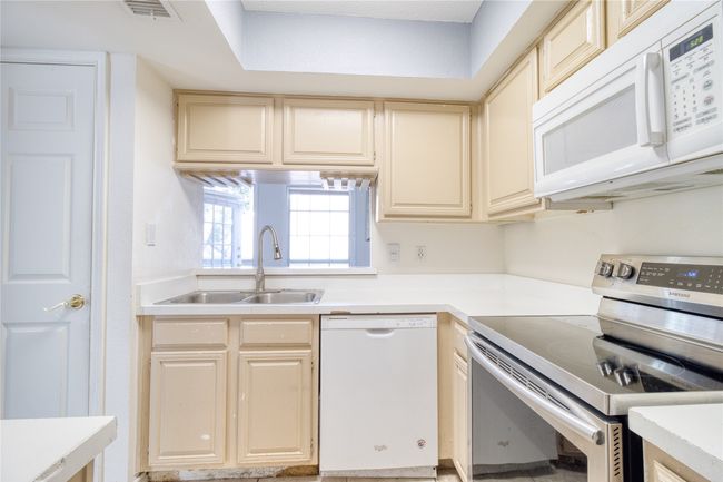 Kitchen with white appliances, cream cabinets, and light countertops | Image 14