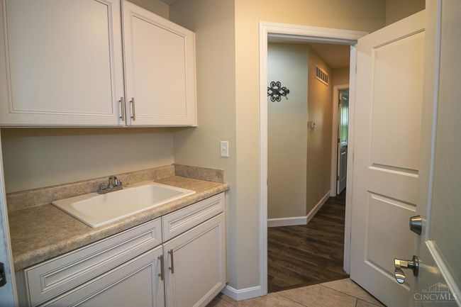 Main floor Laundry Room with built-in cabinets and wash sink, Washer/Dryer hook-up to the right. | Image 27