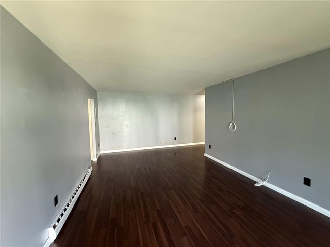 Empty room featuring baseboard heating, baseboards, and dark wood-style floors | Image 8