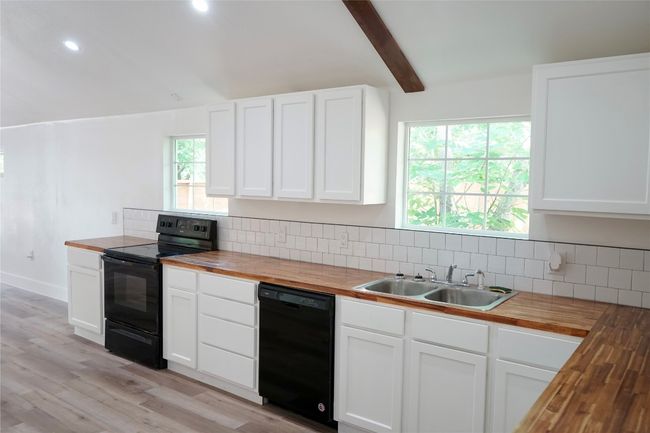 Kitchen featuring wood counters, black appliances, backsplash, light wood finished floors, and recessed lighting | Image 8