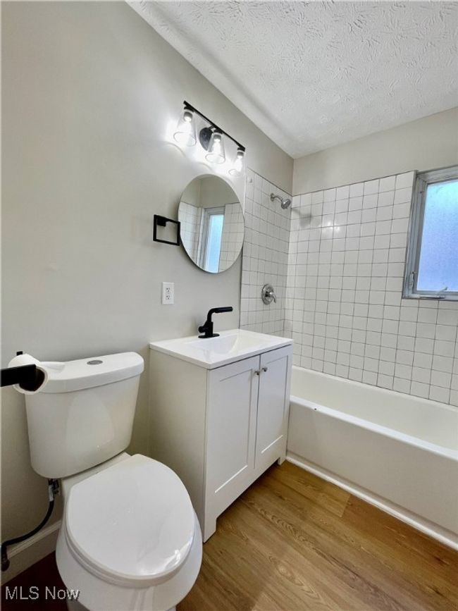 Bathroom featuring wood finished floors, vanity, a textured ceiling, and bathing tub / shower combination | Image 19