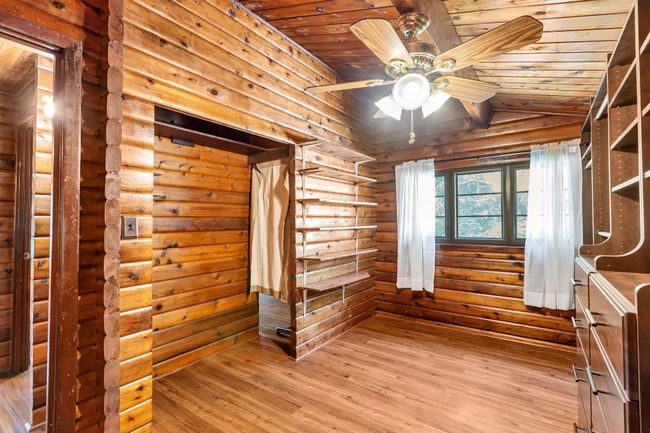 Closet with rustic walls, wood-type flooring, wood ceiling, a ceiling fan | Image 22