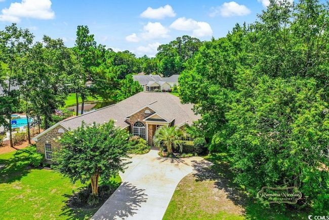 View of front of property with stone siding, a front lawn, view of wooded area, and driveway | Image 5