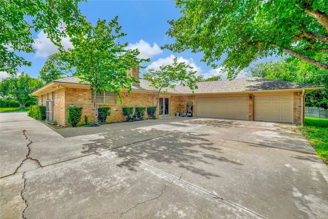 View of front of house with brick siding, concrete driveway, an attached garage, a chimney, and roof with shingles | Image 32