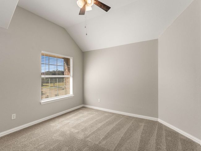 Carpeted empty room with vaulted ceiling, a ceiling fan, and baseboards | Image 35