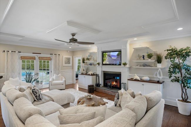 Living area with a wainscoted wall, a fireplace, ornamental molding, a ceiling fan, and dark wood-type flooring | Image 17
