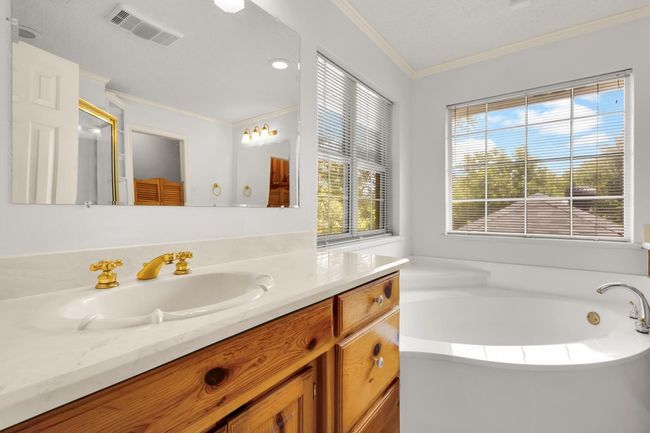 Full bathroom featuring vanity, healthy amount of natural light, a bath, and ornamental molding | Image 15