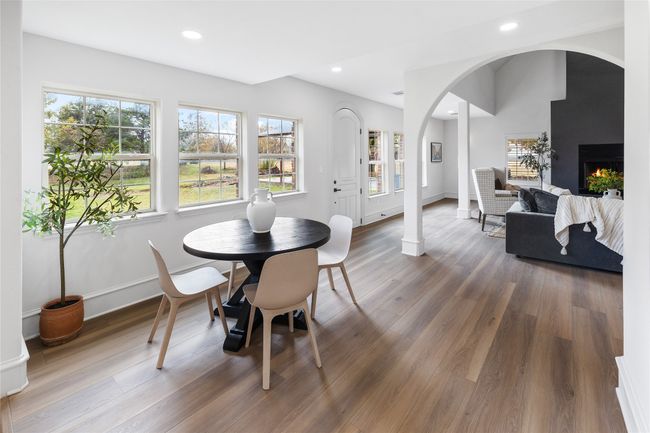 Dining space featuring arched walkways, wood finished floors, recessed lighting, and a warm lit fireplace | Image 20