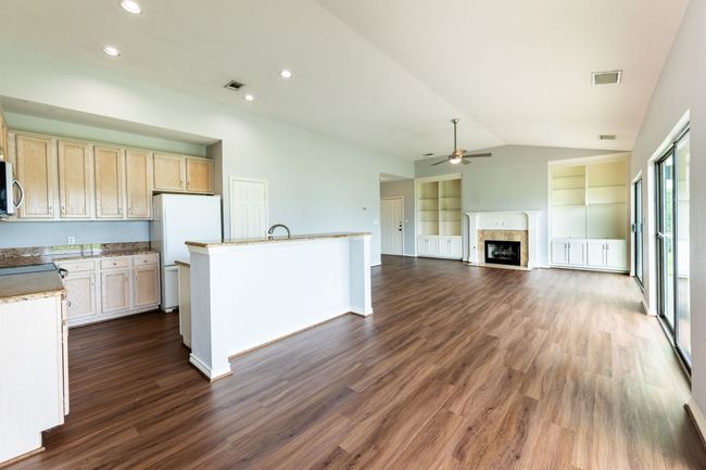 Kitchen featuring ceiling fan, vaulted ceiling, dark wood-style flooring, freestanding refrigerator, and a high end fireplace | Image 9