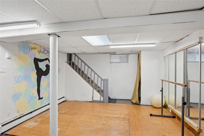 Finished below grade area with a drop ceiling, a baseboard heating unit, and wood finished floors | Image 22