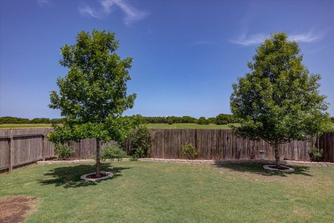 Two mature trees and lovely landscaping around the fence. | Image 37