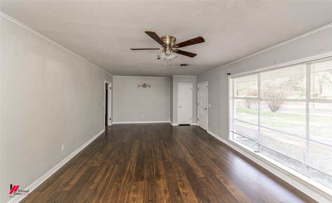 Spare room featuring baseboards, ceiling fan, ornamental molding, and dark wood-style flooring | Image 17