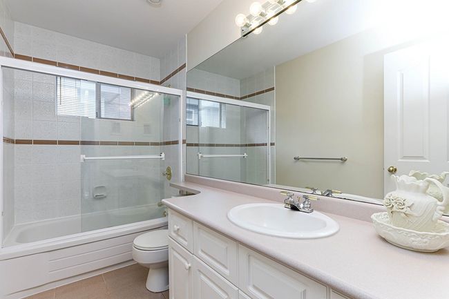 Full bath with tile patterned flooring, shower / bath combination with glass door, vanity, and toilet | Image 35