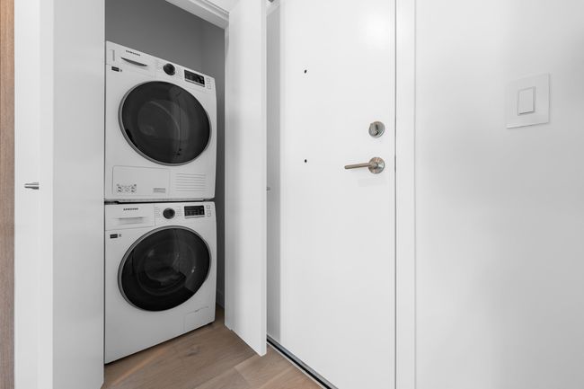 Washroom with stacked washer and clothes dryer and light wood finished floors | Image 14